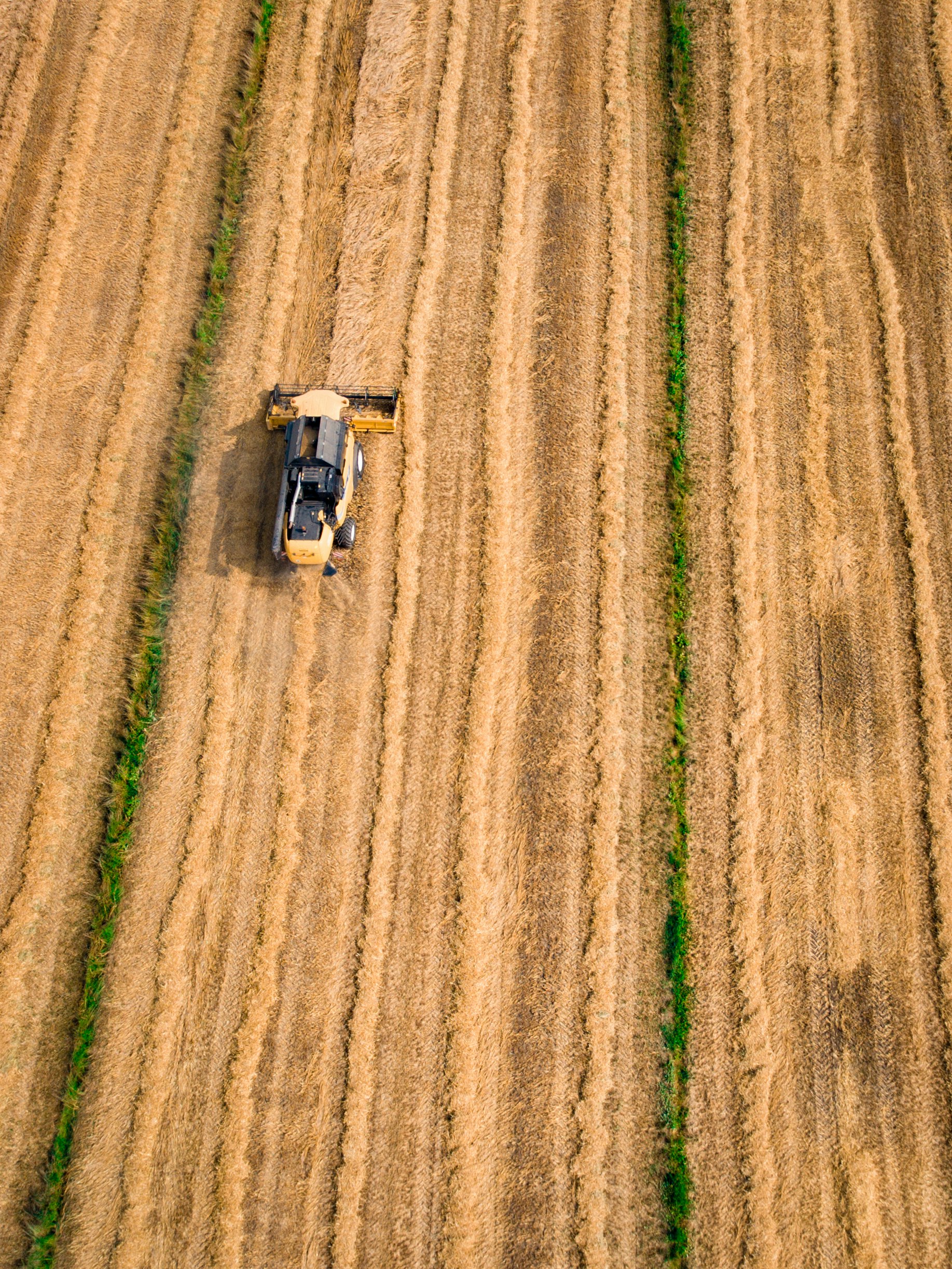 aerial photography of yellow cultivator on brown field